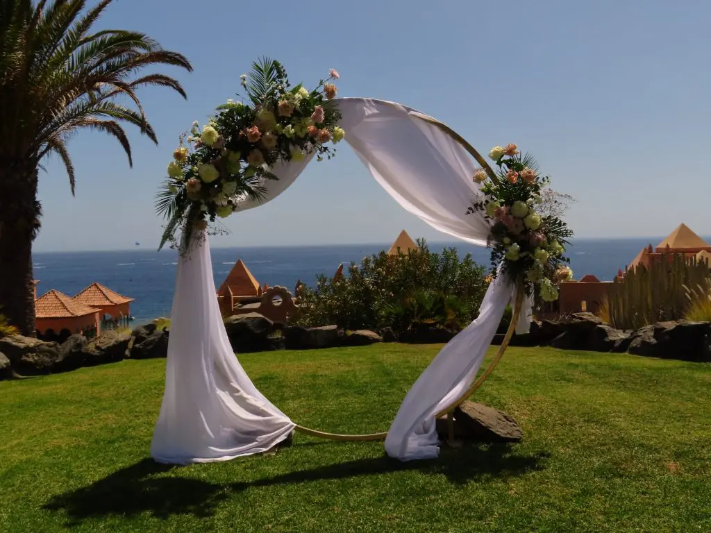 Arco floral de boda en tonos rosa y blanco frente al mar en Tenerife